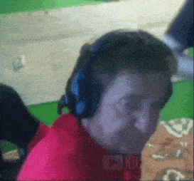 a man wearing headphones and a red shirt is sitting in front of a green screen .