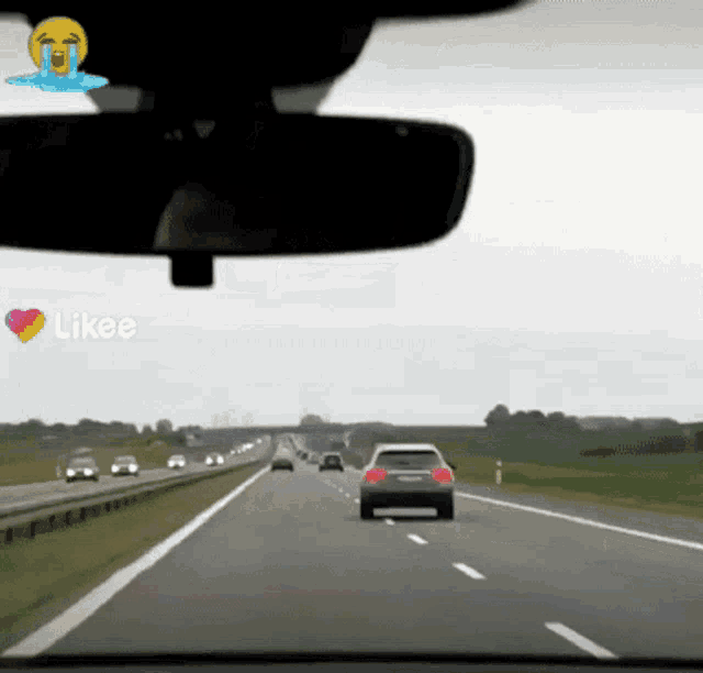 a car is driving down a highway with a crying face in the rear view mirror
