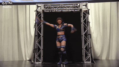 a female wrestler in a blue outfit is walking through a metal structure