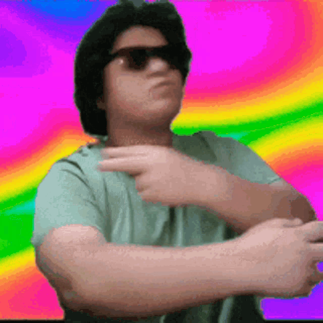 a man wearing sunglasses and a green shirt is pointing at something