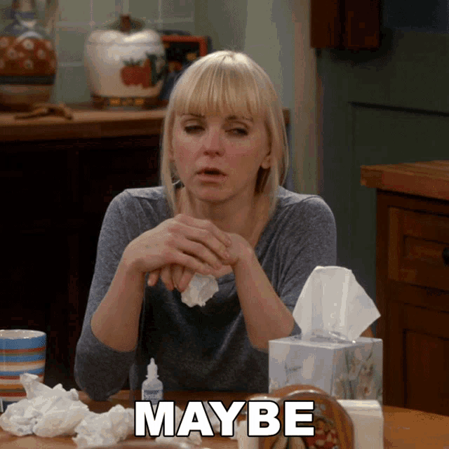a woman sits at a table with a box of tissues and the word maybe on the bottom