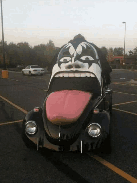 a black car with a kiss face painted on it is parked in a parking lot