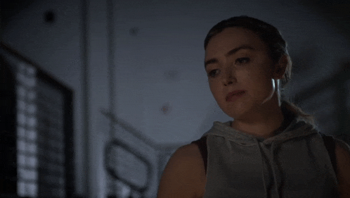 a woman with a ponytail is wearing a grey sweatshirt