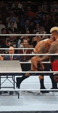 two wrestlers in a ring with one wearing a shirt that says ' smackdown ' on it