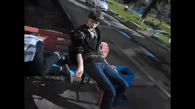 a man sits on a bench next to a trashcan