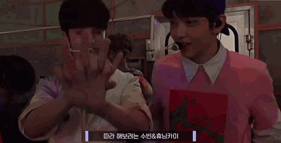 a couple of young men are standing next to each other and making a hand gesture .