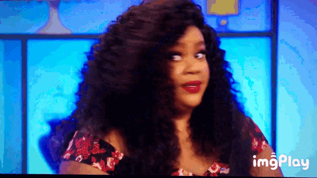 a woman with long curly hair is on a television screen with a blue background and the words imgplay below her