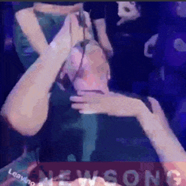 a woman is covering her face with her hands in front of a crowd of people at a concert .