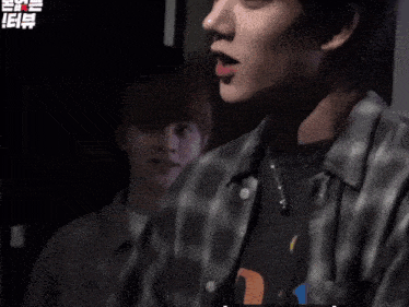 a man wearing a plaid shirt is talking to another man
