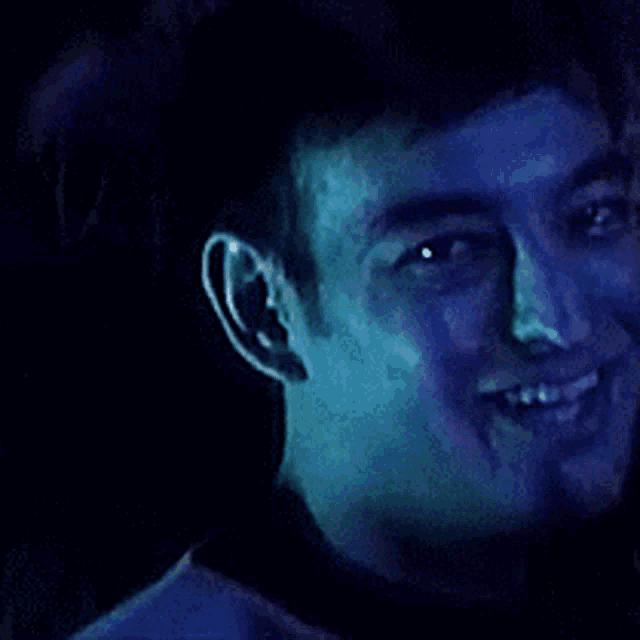 a close up of a man 's face with a blue light behind him