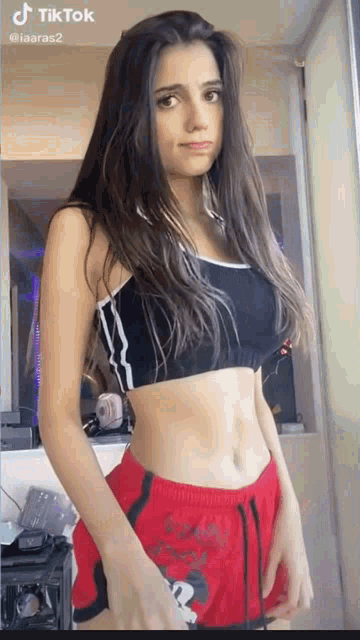 the girl is wearing a black crop top and red shorts .