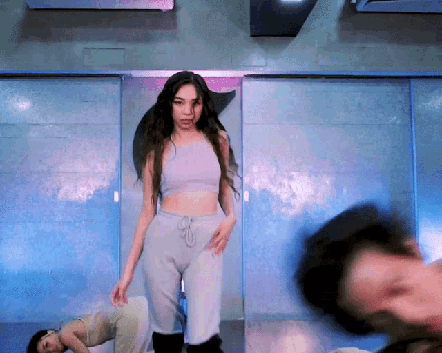 a woman in a crop top and sweatpants is dancing