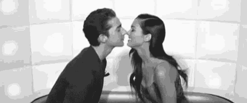 a black and white photo of a man and a woman kissing .