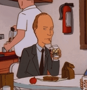 a man in a suit and tie is sitting at a table drinking wine