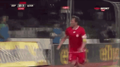 a man in a red shirt is running on a soccer field during a game