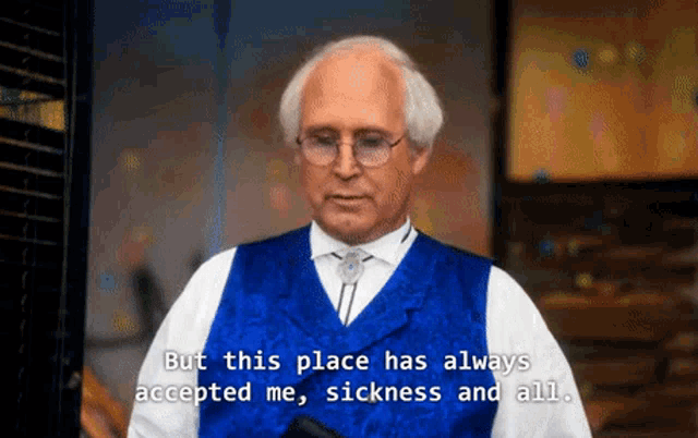 a man wearing glasses and a blue vest says " but this place has always accepted me sickness and all "