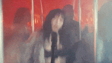 a woman with long hair and bangs is standing in front of a microphone in a red room .