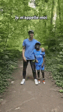 a man and a boy are standing next to each other on a path in the woods .