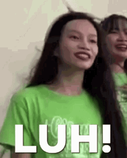 a woman in a green t-shirt is making a funny face while standing next to another woman .