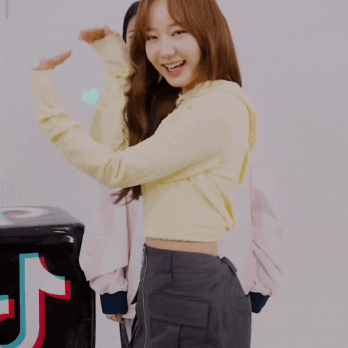 a woman holding a heart in front of a black box with the letter t on it