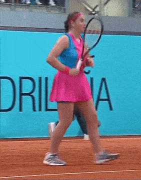 a woman holding a tennis racquet in front of a sign that says lacoste