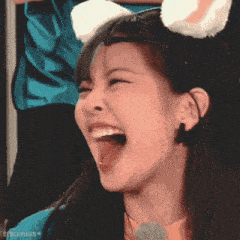 a girl wearing a cat ear headband is laughing with her mouth wide open .