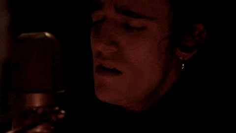 a close up of a person 's face in front of a microphone with their eyes closed .