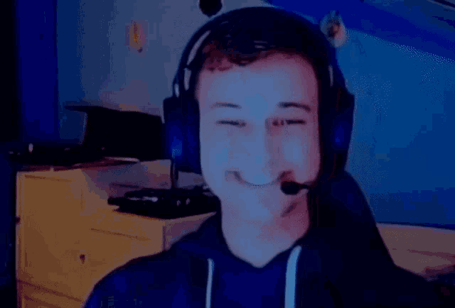 a man wearing headphones and a microphone is smiling and making a heart shape with his hands .