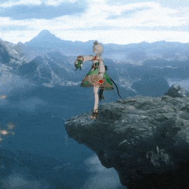 a girl in a green dress is standing on a rocky cliff with mountains in the background