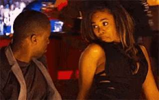 a man and a woman are standing next to each other in a bar .