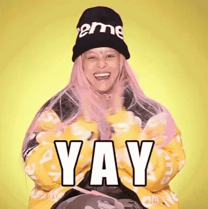 a woman with pink hair is wearing a supreme hat and a yellow jacket and says yay .