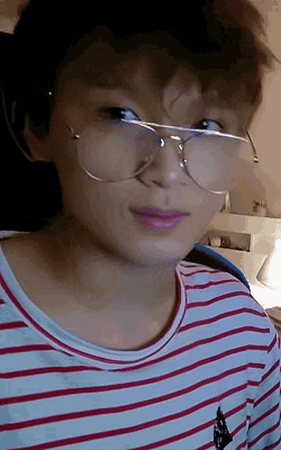 a young boy wearing glasses and a striped shirt looks at the camera