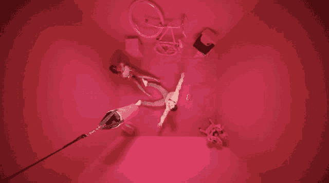 a man is laying on the floor in a pink room with a bicycle in the background