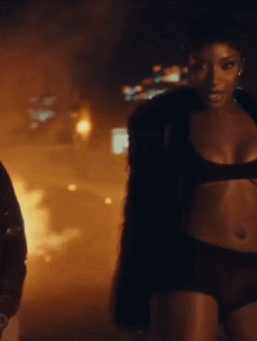 a woman in lingerie is standing next to a man in a fur coat .