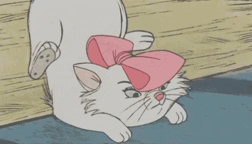 a white cat with a pink bow on its head is laying down .
