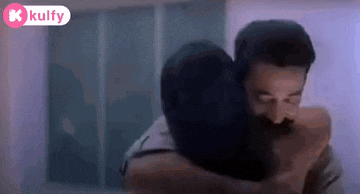 a man and a woman are hugging each other in front of a window .