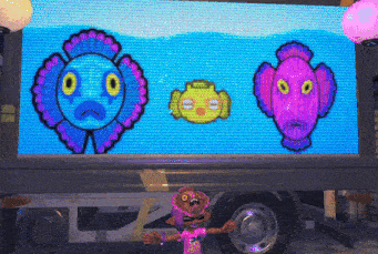 a video game character is standing in front of a large screen displaying cartoon characters .