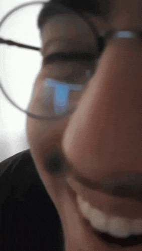 a close up of a person 's face wearing glasses and smiling