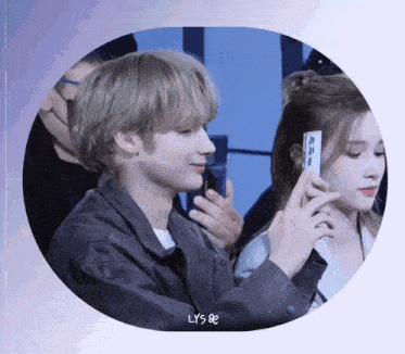 a man taking a picture of a woman with his phone with lys written in the corner