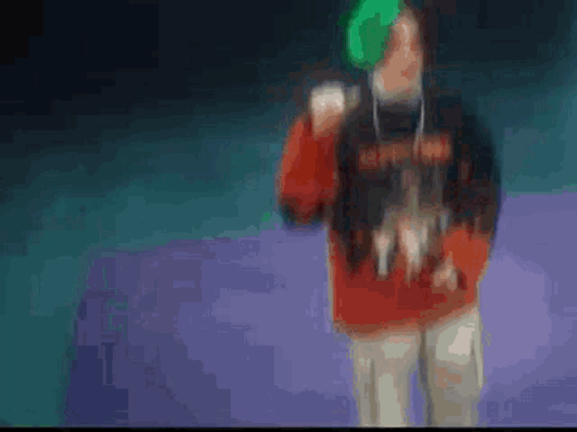a blurry picture of a person wearing a red and black sweater and a green hat .