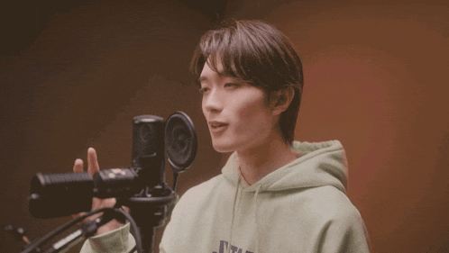 a young man singing into a microphone with his eyes closed