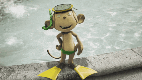 a stuffed monkey wearing yellow flippers and a goggles stands next to a pool