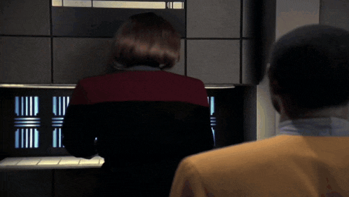 a woman in a red jacket is looking at a monitor