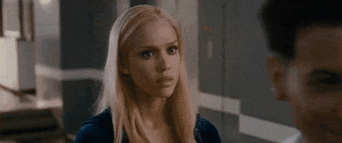 a woman with blonde hair is standing next to a man in a room .