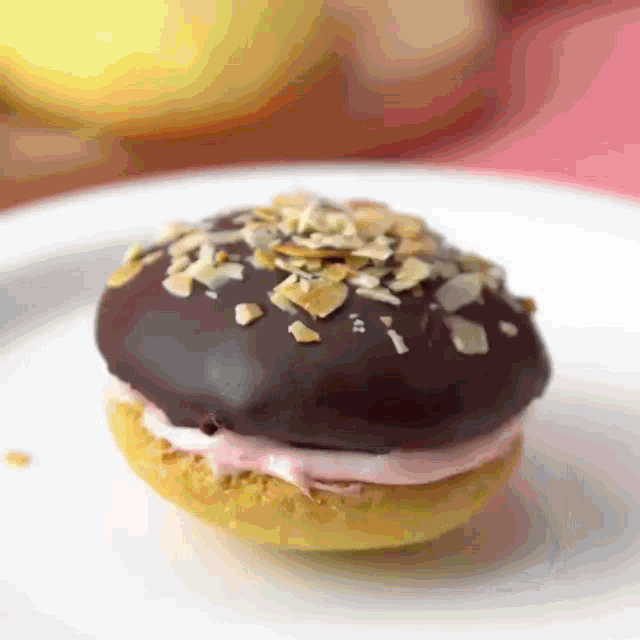 a donut with chocolate frosting and nuts on top of it on a white plate
