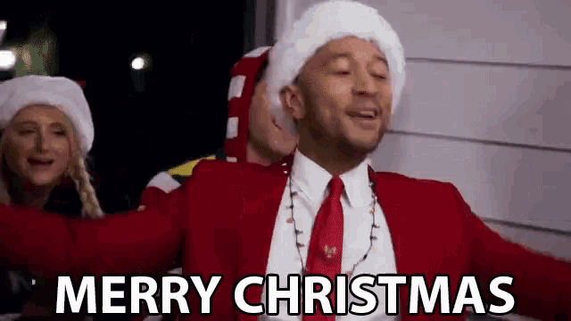 a man in a red suit and tie is wearing a santa hat and a christmas sweater .