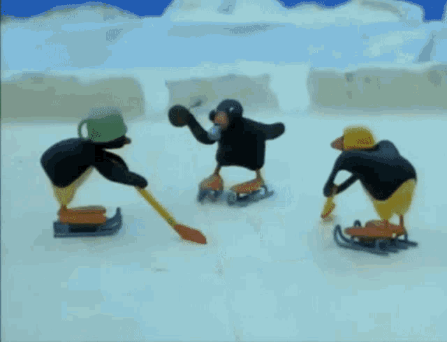a couple of penguins are playing ice hockey on a rink