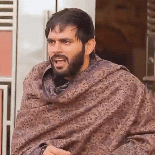 a man with a beard is wrapped in a blanket and making a face