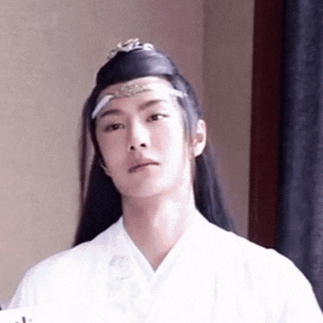 a man with long hair wearing a crown and a white shirt
