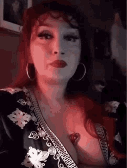 a woman with red hair is wearing hoop earrings and a black dress